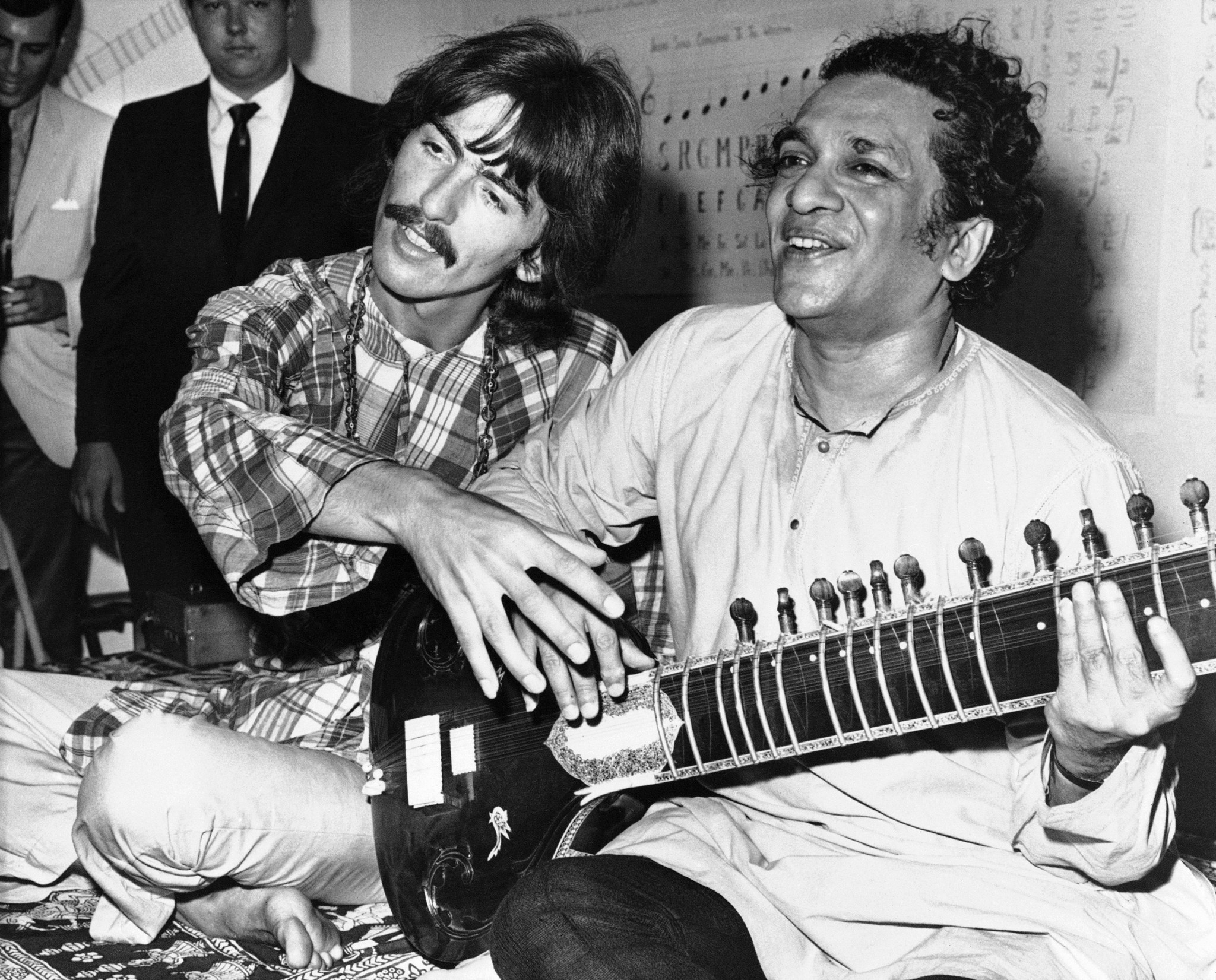 George Harrison, left, sits cross-legged with his musical mentor, Ravi Shankar of India, on Aug. 3, 1967 in Los Angeles, as Harrison explains to newsmen that Shankar is teaching him to play the sitar.