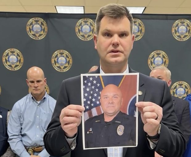 In this image made from video shown in the Blount County Sheriff's Office's Facebook page, an official shows a picture of Deputy Greg McCowan in Maryville, Tenn., Friday, Feb. 9, 2024. Authorities in eastern Tennessee were searching early Friday for a suspect they say was involved in a shooting that killed one sheriff's deputy and left another wounded. (Blount County Sheriff's Office via AP)