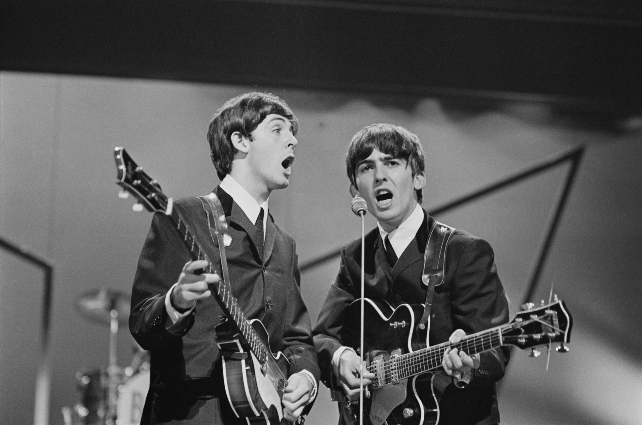 Paul McCartney and George Harrison of the Beatles perform on stage at the London Palladium on October 13, 1963.