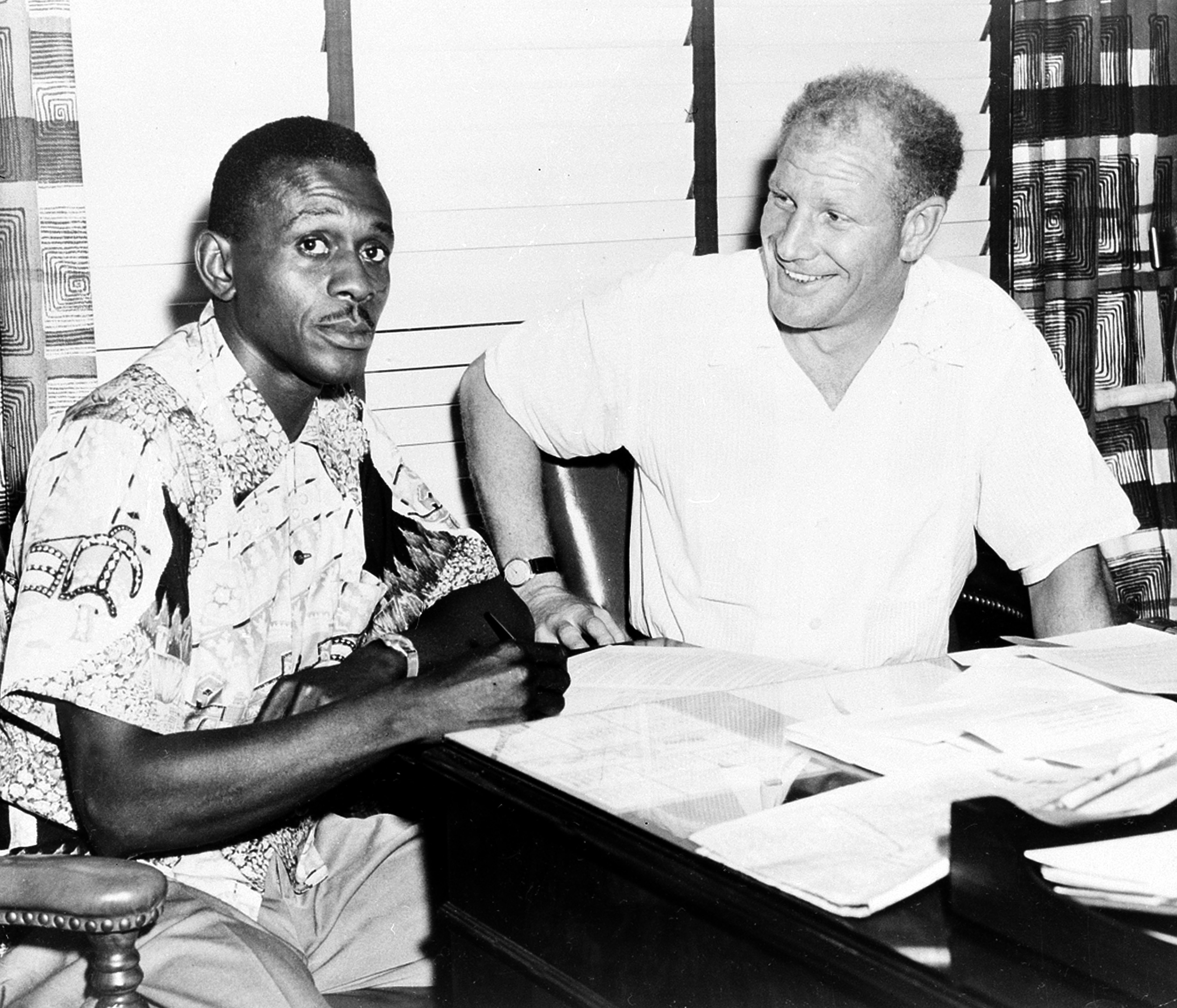 Pitcher Satchel Paige signs the contract for his return to major league baseball, starting for the Browns, in St. Louis, on July 18, 1951. Next to him is Bill Veeck, the new owner of the team.