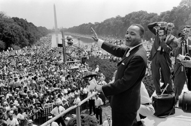 Rev. Martin Luther King Jr. waves to supporters 28 August 1963 on the Mall in Washington DC (Washington Monument in background) during the "March on Washington", where King delivered his famous "I Have a Dream" speech, which mobilized supporters of desegregation and prompted the Civil Rights Act of 1964. (AFP via Getty Images)