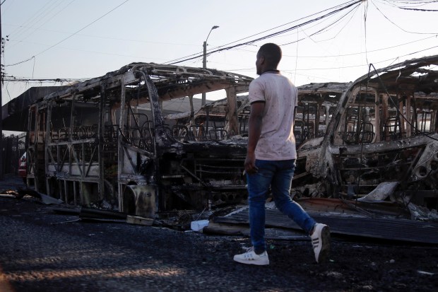 A man walks next to burnt vehicles after a fire that affected the hills in Viña del Mar, Chile on February 3, 2024. The region of Valparaoso and Viña del Mar, in central Chile, woke up on Saturday with a partial curfew to allow the movement of evacuees and the transfer of emergency equipment in the midst of a series of unprecedented fires, authorities reported. (Photo by Javier TORRES / AFP) (Photo by JAVIER TORRES/AFP via Getty Images)