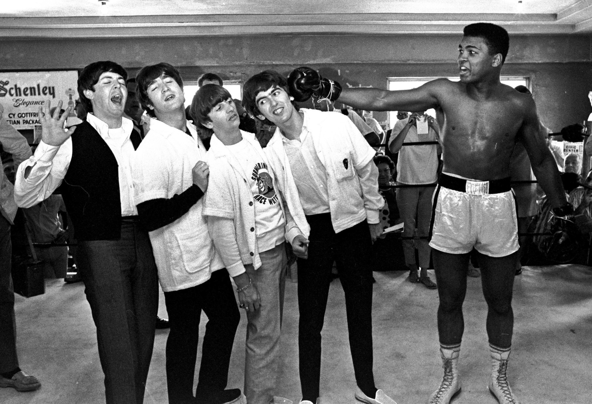 Paul McCartney, John Lennon, Ringo Starr, and George Harrison of The Beatles take a fake blow from Muhammad Ali, at the time known as Cassius Clay, while visiting the heavyweight contender at his training camp in Miami Beach, Fla. on Feb. 17, 1964.
