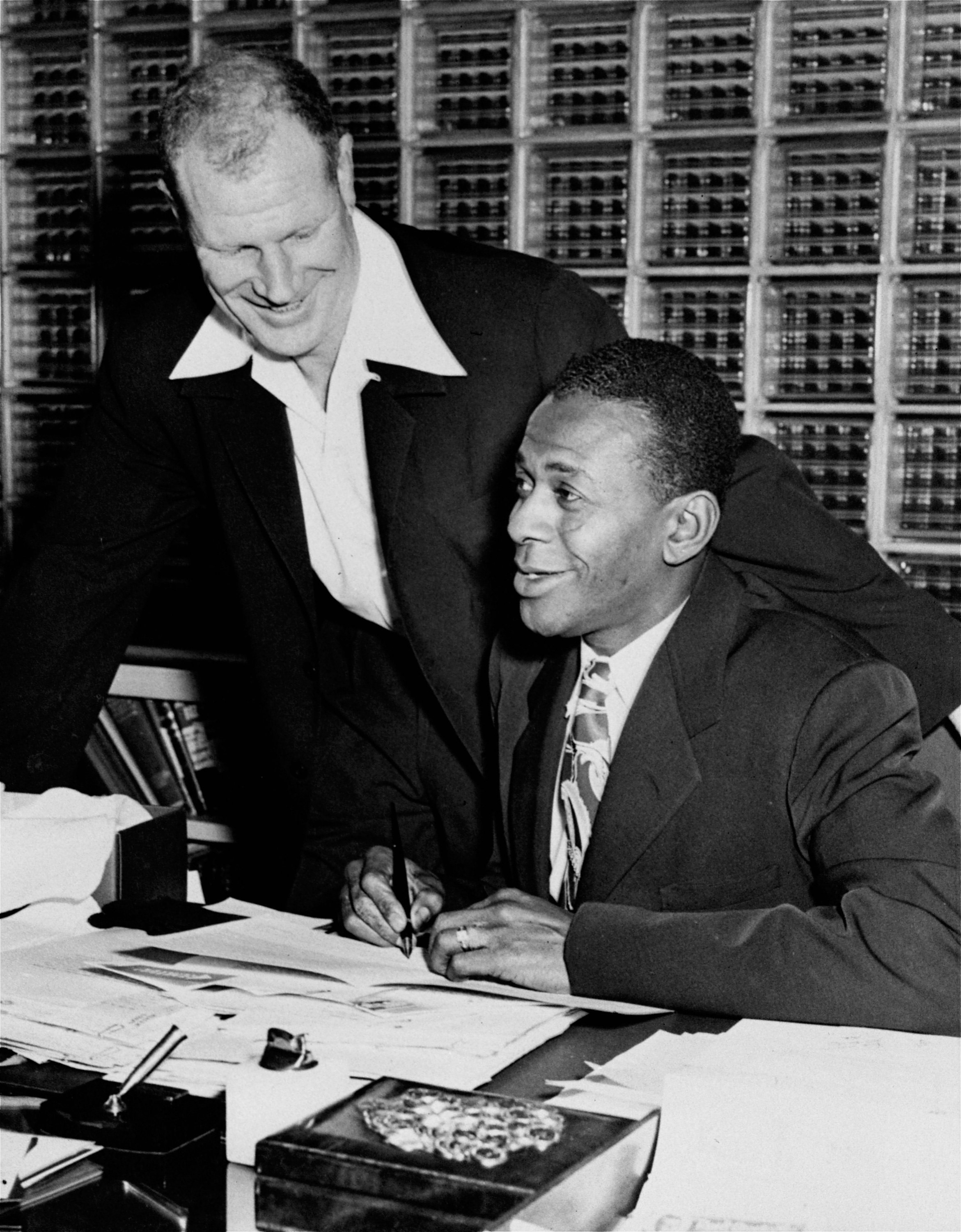 Satchel Paige signs his 1953 contract with the St. Louis Browns as owner Bill Veeck looks on on Jan. 10, 1953. The right-handed hurler reportedly received between $25,000 and $30,000. It was the third Brownie contract for Paige, who first came to the Browns in 1951 after Veeck had taken over the club.