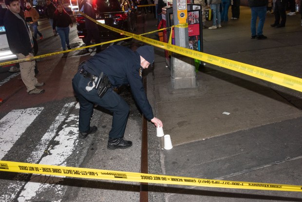 A police officer marks evidence after a woman was shot inside the JD Sports store on Broadway and 41st Street in Times Square, Manhattan, New York City on Thursday, Feb. 8, 2024. (Gardiner Anderson for New York Daily News)