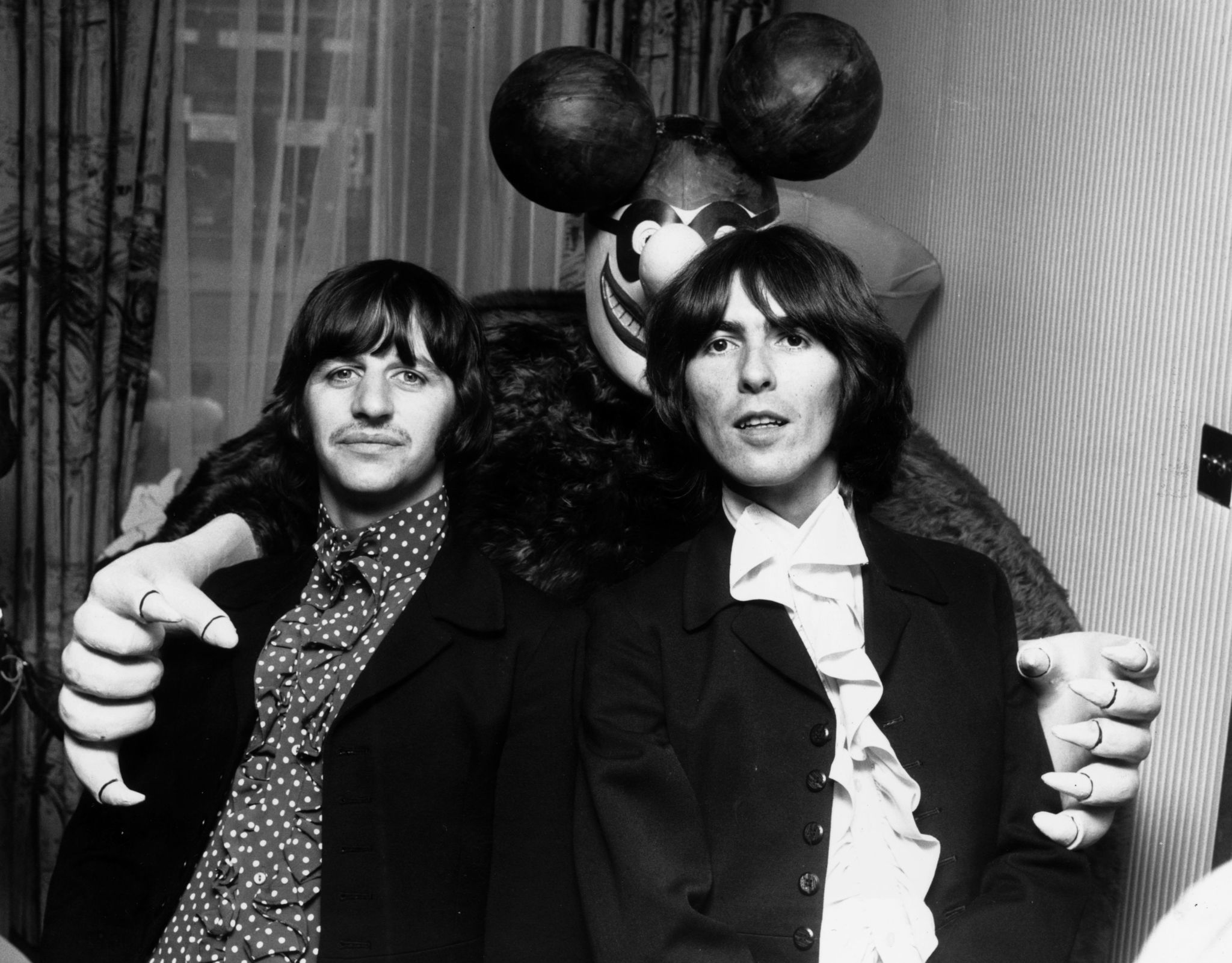 Ringo Starr (L) and George Harrison are embraced by a 